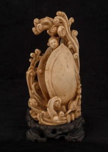 A Chinese carved ivory statue of a female standing nude in waves and clam shell, on wooden stand, early to mid 20th century, 22cm high overall