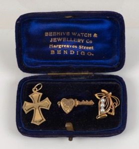 A 15ct yellow gold crucifix pendant, an 18ct gold and pearl pendant, and a 10ct gold lined love heart and key brooch, housed in a vintage branded box "BEEHIVE WATCH & JEWELLERY CO. HARGREAVES STREET BENDIGO", (3 items), ​​​​​​​the crucifix 2 grams