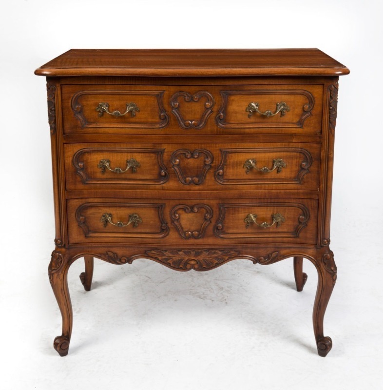 A French Provincial Louis XV style walnut three drawer commode with shallow serpentine front, carved drawer fronts and scroll cabriole legs, circa 1910 73cm high, 70cm wide, 40cm deep.