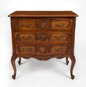 A French Provincial Louis XV style walnut three drawer commode with shallow serpentine front, carved drawer fronts and scroll cabriole legs, circa 1910 73cm high, 70cm wide, 40cm deep.