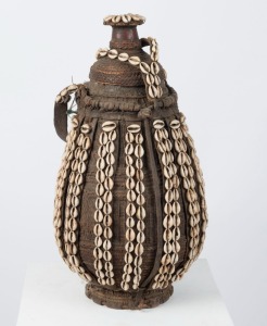 A tribal storage vessel, of carved wood, hide, cane and shell decoration, West African origin, 49cm high