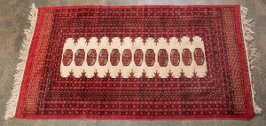 A hand-knotted wool tribal rug on red ground with cream background in the centre, ​​​​​​​177 x 92cm