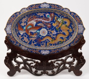A Chinese blue cloisonne platter with dragon and phoenix decoration, on wooden stand, 20th century, 34cm wide