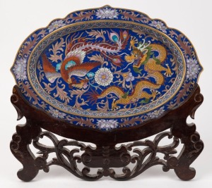 A Chinese blue cloisonne platter with dragon and phoenix decoration, on wooden stand, 20th century, ​​​​​​​34cm wide