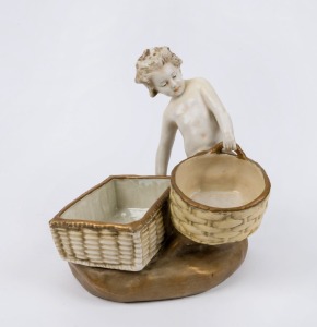 AMPHORA Austrian porcelain figural bowl in the form of a child holding two baskets, late 19th century, stamped "Imperial Amphora, Turn, Austria" with crown mark, ​​​​​​​22cm high