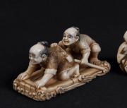 Three Japanese carved ivory netsuke of a reclining man, a drum figural group, and two crouching figures, 20th century, ​​​​​​​the largest 5cm long - 2