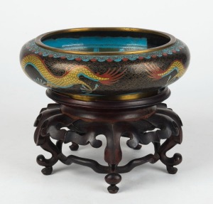  A Chinese cloisonne dragon bowl with four character seal mark to base on a carved timber stand (stand A/F), 19th/20th century, the bowl 6.5cm high, 20.5cm diameter, 17cm high overall