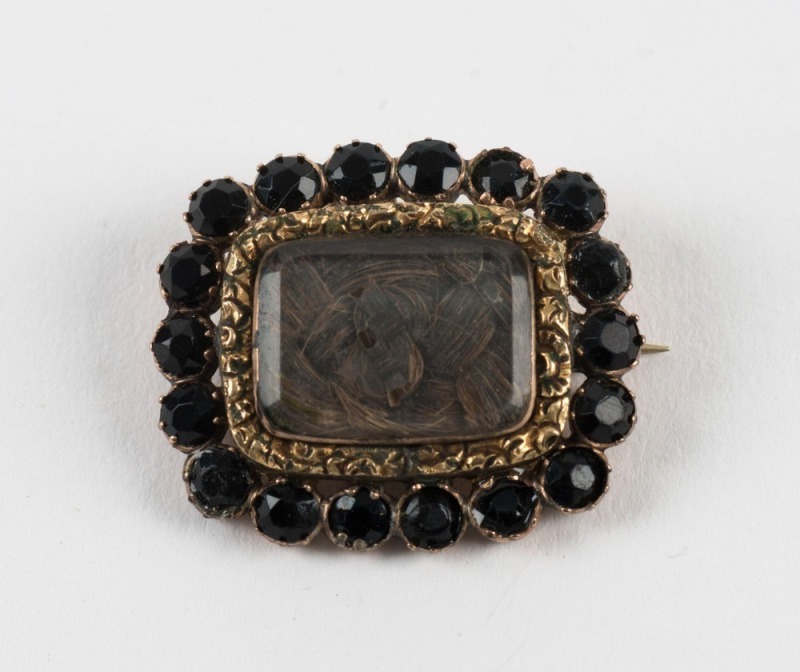 An antique mourning brooch, rose gold and garnet with woven hair window, 19th century, ​​​​​​​3.3cm wide