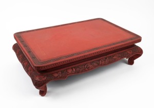 A Chinese red lacquered stand with carved decoration, 19th/20th century, 15cm high, 52cm wide, 35cm deep