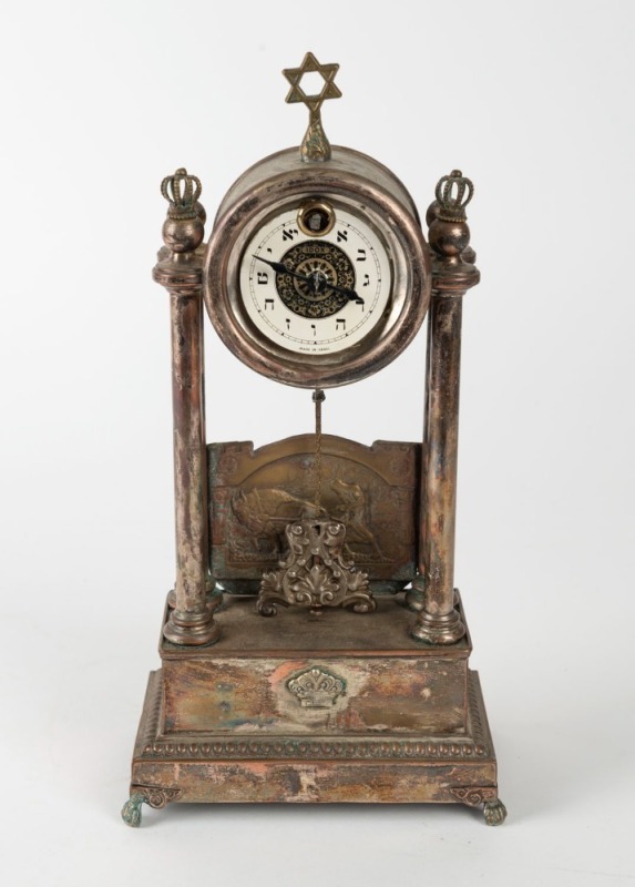 JUDAICA: Idox German mantel clock, surmounted by a star of David with Torah crown finials, and featuring a brass panel depicting a farmer with an ox tilling the soil, with the biblical verse (in Hebrew) "Work the land and you will be satisfied with bread"