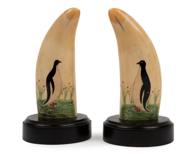 A pair of whale's tooth ornaments on stands adorned with folk art penguin paintings, ​​​​​​​15cm high overall