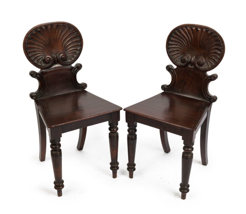 A pair of early Colonial Australian cedar hall chairs with finely carved shell backs and applied roundels, New South Wales origin, circa 1840, 87cm high. ​​​​​​​PROVENANCE: The Windeyer Family, New South Wales.