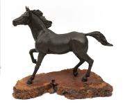 A cast bronze horse on a burl wood base, 39cm high, 45cm long.