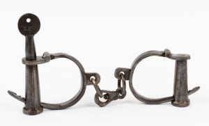 A pair of antique style metal handcuffs with key, late 20th century, ​​​​​​​29cm wide