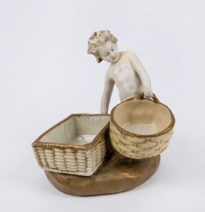 AMPHORA Austrian porcelain figural bowl in the form of a child holding two baskets, late 19th century, stamped "Imperial Amphora, Turn, Austria" with crown mark, 22cm high