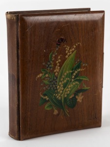 An old-time leather-bound photo album with hand-painted wooden front cover containing a range of cabinet-card and carte-de-visite size portraits; many Victorian photographers noted as well as two tintypes. (150+ images).