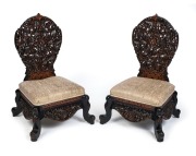 A pair of antique Anglo-Indian ebony nursing chairs with ornately carved and pierced decoration, 19th century, 89cm high