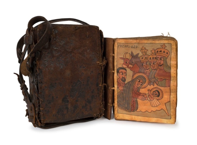 Ethiopian Orthodox manuscript religious book, hand-painted and written on vellum with carved timber boards, housed in original leather pouch, 19th century,18cm high overall