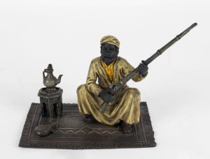 A cold painted bronze statue of a seated Bedouin with gun, 11cm high, 16cm wide