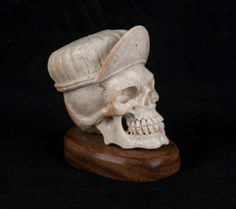 A carved antler skull statue on wooden base, 20th century, 7cm high overall