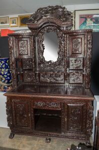 An antique Chinese sideboard, ornately carved with ebonised finish, 19th/20th century, note: mirror broken and back damaged. 210cm high, 152cm wide, 68cm deep