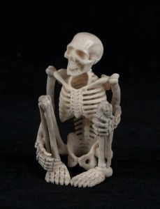 A carved antler statue of a squatting skeleton figure, 20th century, 8cm high