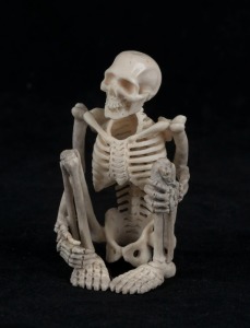 A carved antler statue of a squatting skeleton figure, 20th century, 8cm high 