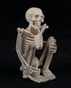 A carved antler statue of a squatting skeleton figure, 20th century, 8cm high  - 2