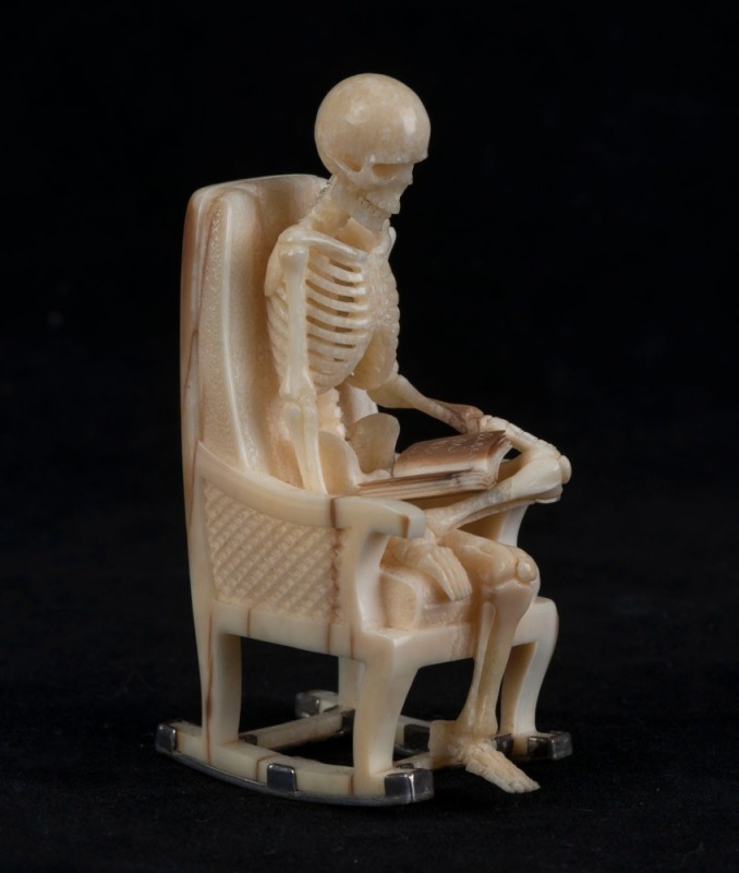 A carved antler and silver statue of a skeleton figure in a rocking chair, 20th century, 9cm high 