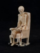 A carved antler and silver statue of a skeleton figure in a rocking chair, 20th century, 9cm high  - 2