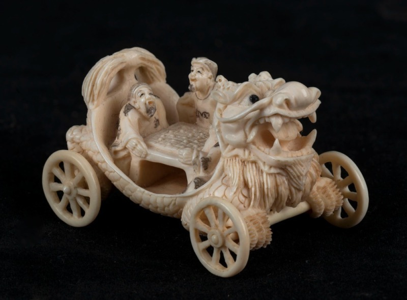 A Japanese carved ivory netsuke dragon cart with seated figures, Meiji period, 20th century, 5.5cm long