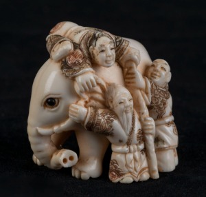 A Japanese carved ivory and hand-coloured netsuke of an elephant and figures, Meiji period, 20th century, ​​​​​​​4cm high