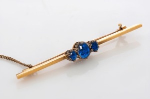 An antique 18ct yellow gold and platinum bar brooch, set with three blue sapphires, circa 1900, stamped "18ct, PLAT.", ​​​​​​​4.9 grams