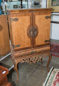 A vintage cocktail cabinet with decorative carving and gilt metal mounts, 20th century, 145cm high, 80cm, wide, 40cm deep