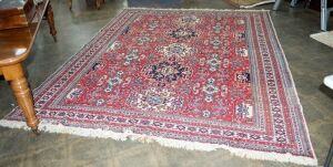 A Persian hand-knotted wool rug with red ground, 350 x 265cm