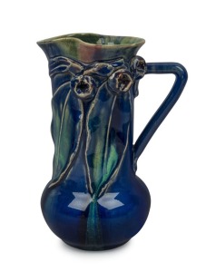 REMUED blue and green glazed pottery jug with a blush of pink highlights, adorned with applied gumnuts, leaves and branch handle, incised "Remued, Hand Made, 153/M", ​​​​​​​19.5cm high