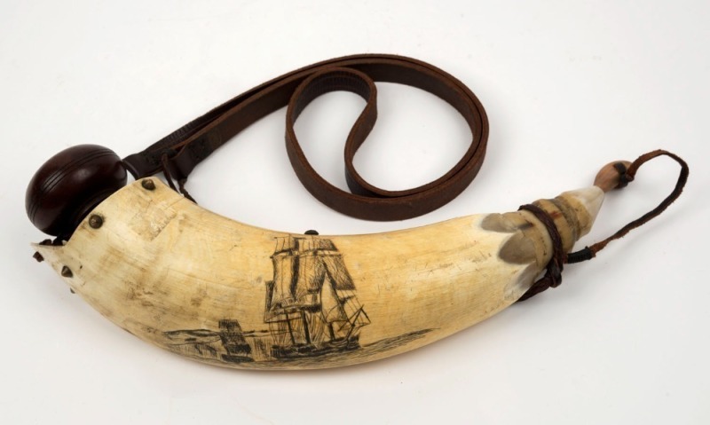 A scrimshaw powder horn adorned with tallships, later leather strapping, 35cm long