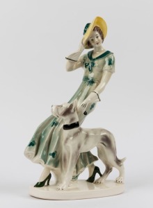 A Continental Art Deco porcelain statue of a lady in a green dress with hound, 38.5cm high