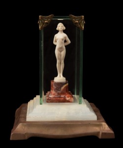 A Continental Art Deco carved ivory statue of a standing female nude mounted on rouge marble base and housed in a bespoke glass cabinet on marble and bronze base, circa 1930, the case 16cm high overall