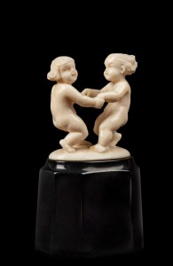 An Austrian Art Deco carved ivory figural group statue of dancing putti figures, mounted of faceted ebonised base, signed "S. W., 1931", 8cm high overall