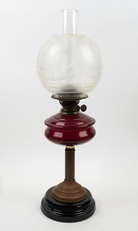 An antique oil lamp with ruby glass font, double burner, brass column, black glass base, spherical glass shade and chimney, 19th/20th century, 62cm high 