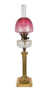 An antique kerosene oil lamp with brass Corinthian column base, faceted crystal font, black button double burner, original acid etched ruby glass shade and chimney, 19th century,  85cm high overall