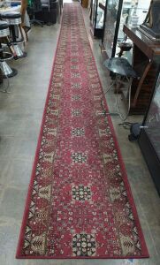 A red patterned hall runner rug,  12 metres long, 80cm wide