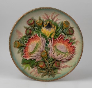 A hand-painted chalkware floral plaque, circa 1930,  36cm diameter