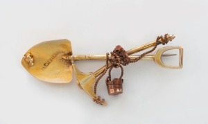 A South African gold miner's brooch, yellow and rose gold crossed pick and shovel with bucket and nugget, 5.7cm wide, 4.5 grams