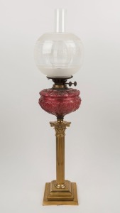 A banquet lamp with embossed ruby glass font, double burner, brass column base and replacement etched glass shade, 81cm high