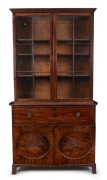 A handsome Georgian two door library bookcase in the Hepplewhite style, mahogany with ebony string inlay and oval recessed panel doors, late 18th century, 243cm high, 129cm wide, 57cm deep