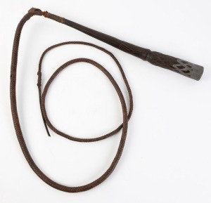 An antique Australian stock whip with Aboriginal carved and lead weighted handle, 19th/20th century, the handle 44cm long