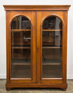 An antique Australian cedar bookcase with arch-top glazed doors and a plinth base on bun feet, 19th century, 154cm high, 119cm wide, 52.5cm deep