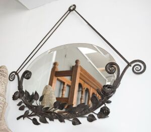 A French Art Deco oval mirror with floral wrought iron decoration, circa 1930, 83cm wide